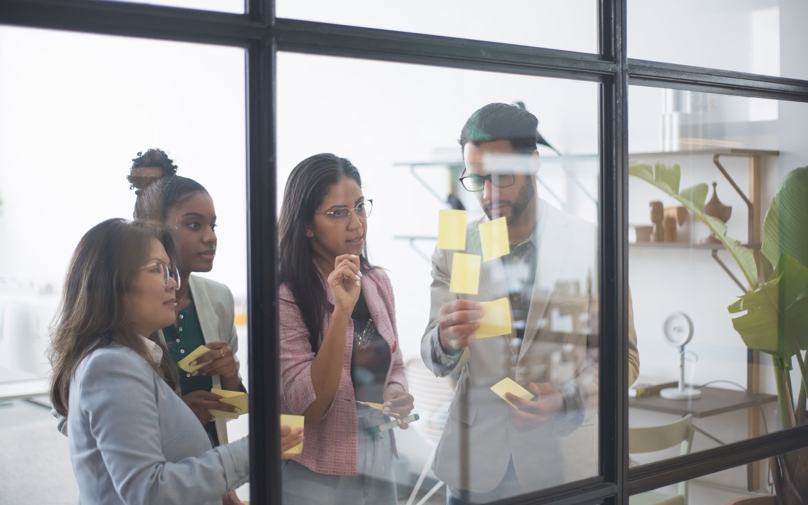 Et team bygger en plan sammen med post-its på en glasvæg